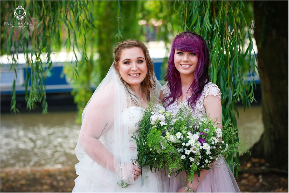 Wedding party poses under a weeping willow tree with white floral bouquets.
