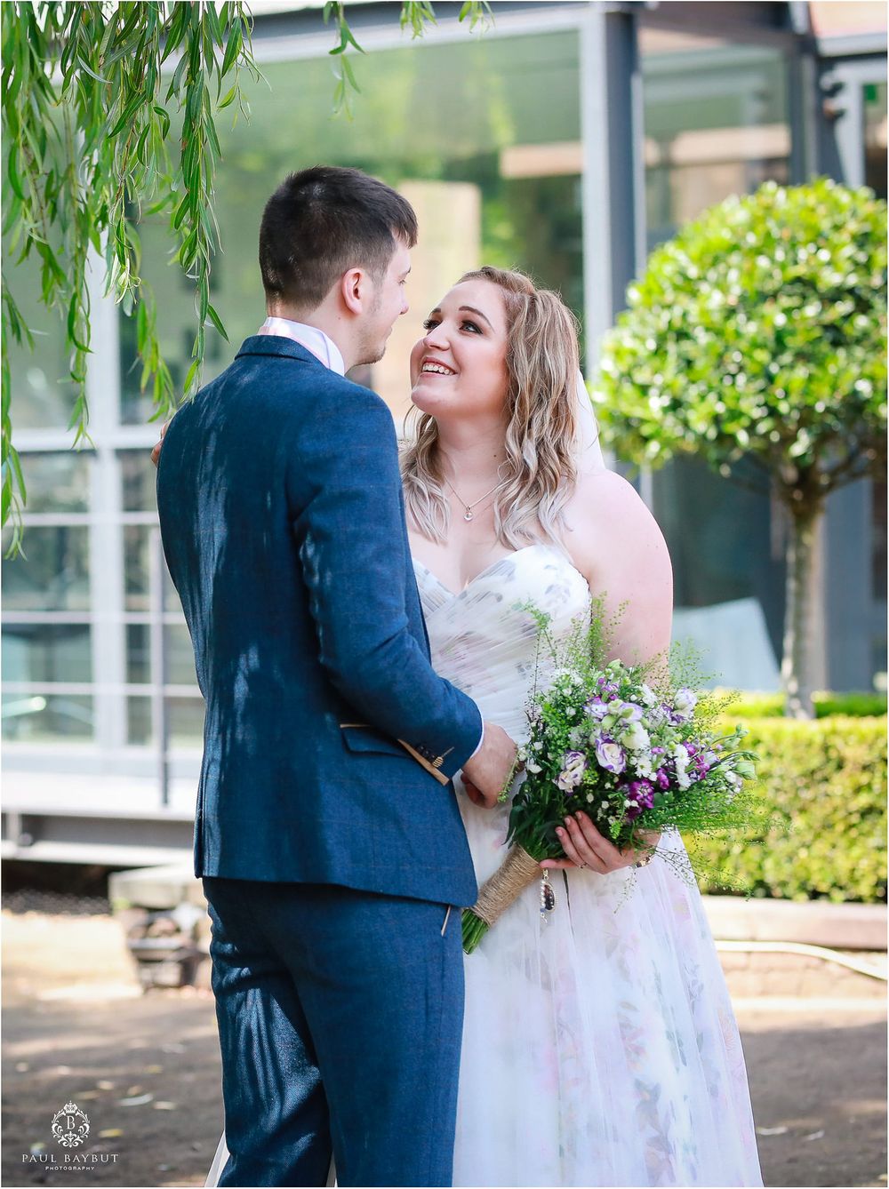 Intimate wedding portrait with couple sharing tender moment against garden backdrop.