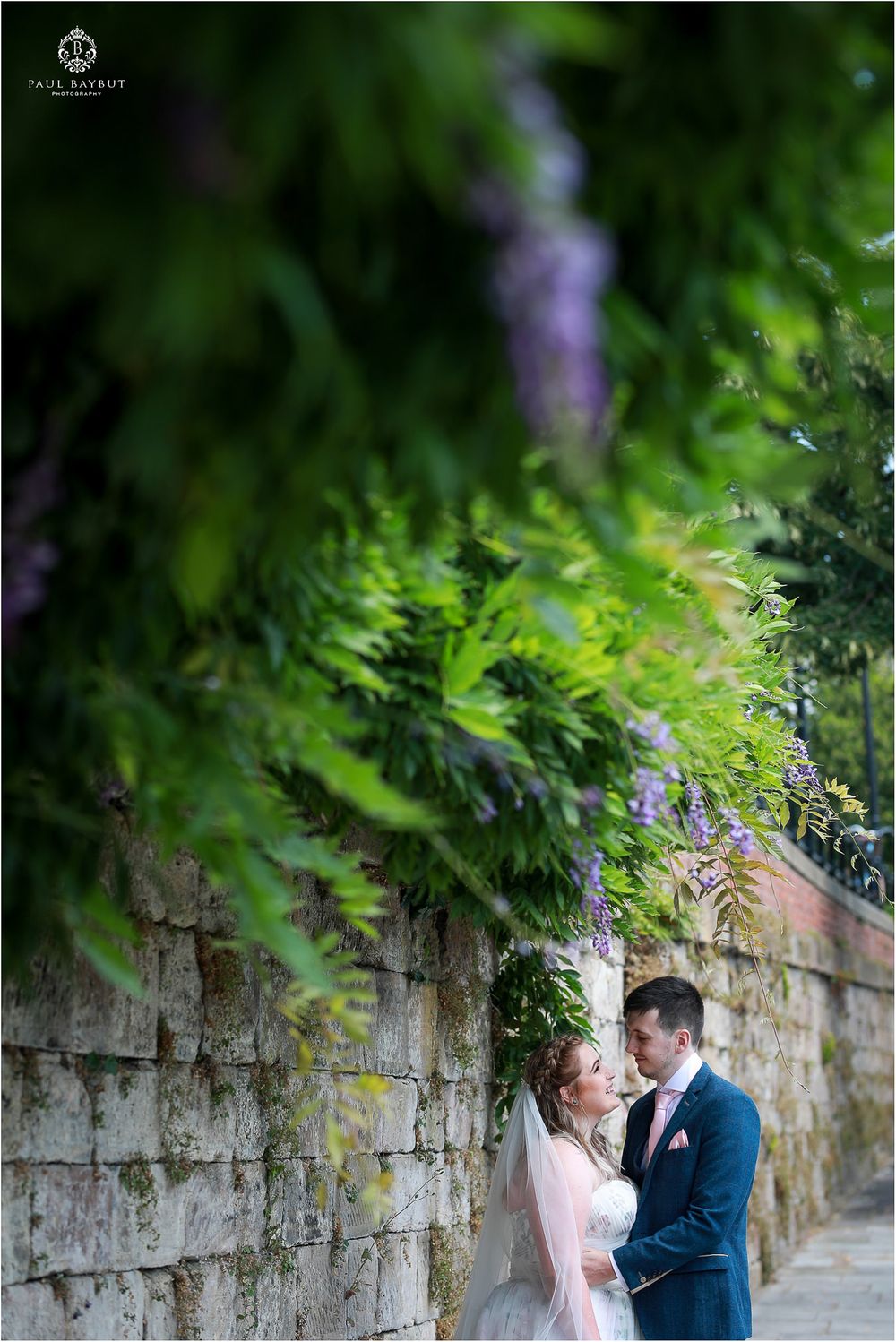 Artistic wedding portrait framed by blurred green foliage.