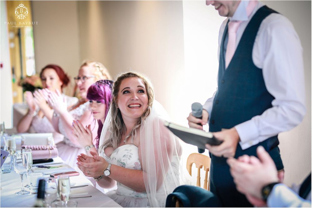 Celebratory moment at wedding reception with guests seated at decorated tables.