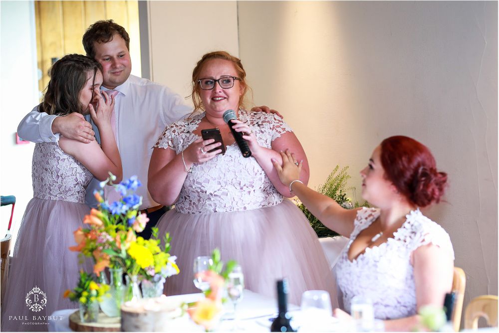 Candid moment of laughter and joy during wedding reception speeches.
