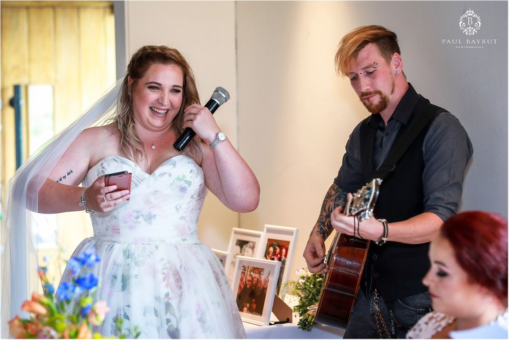 Live acoustic music performance during wedding reception with white floral decorations.