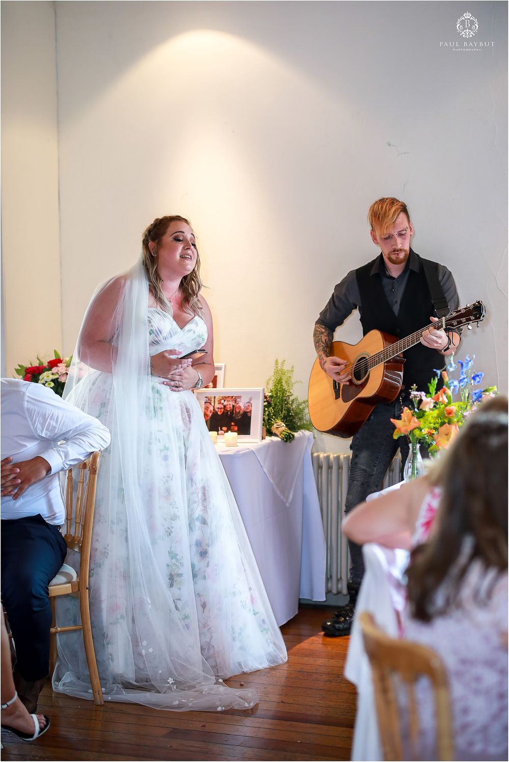 A musical performance during a wedding ceremony with the bride in white dress and a guitarist playing acoustic guitar.