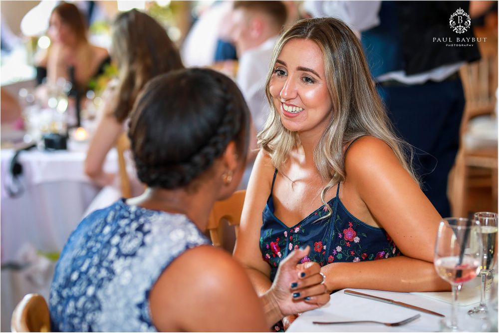 Two wedding guests engaged in conversation at an elegant reception dinner.