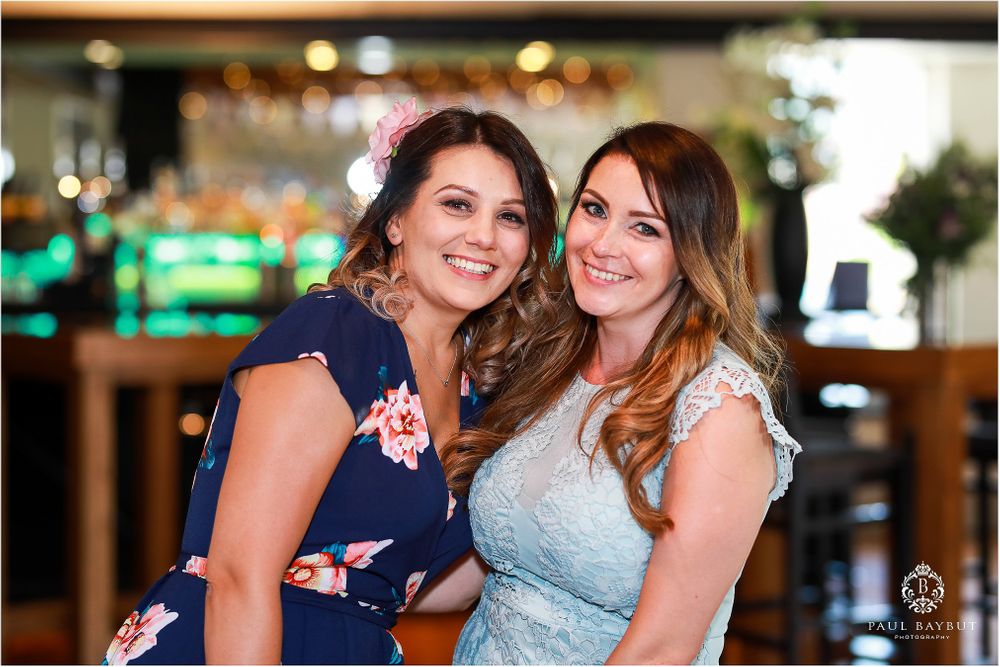 Two wedding guests in navy and light blue dresses pose together at the reception.