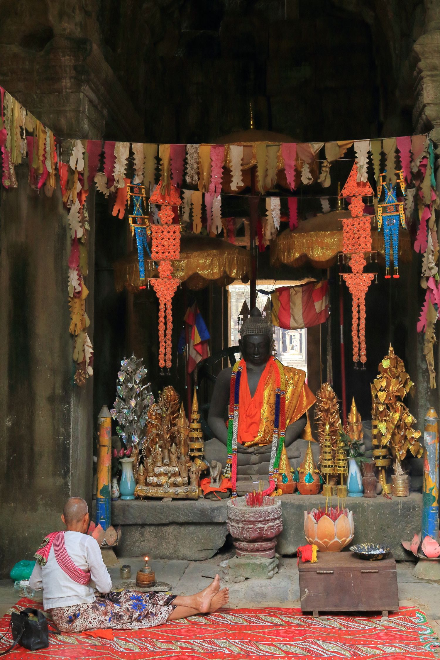 Colorful religious shrine with statues and decorative banners in a temple setting.