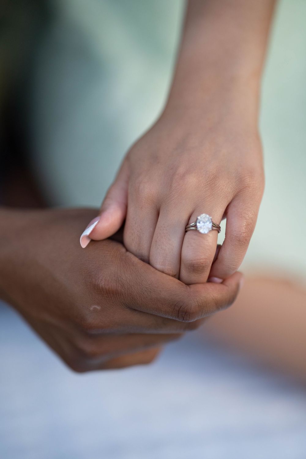 Close-up shot of hands displaying an elegant engagement ring.