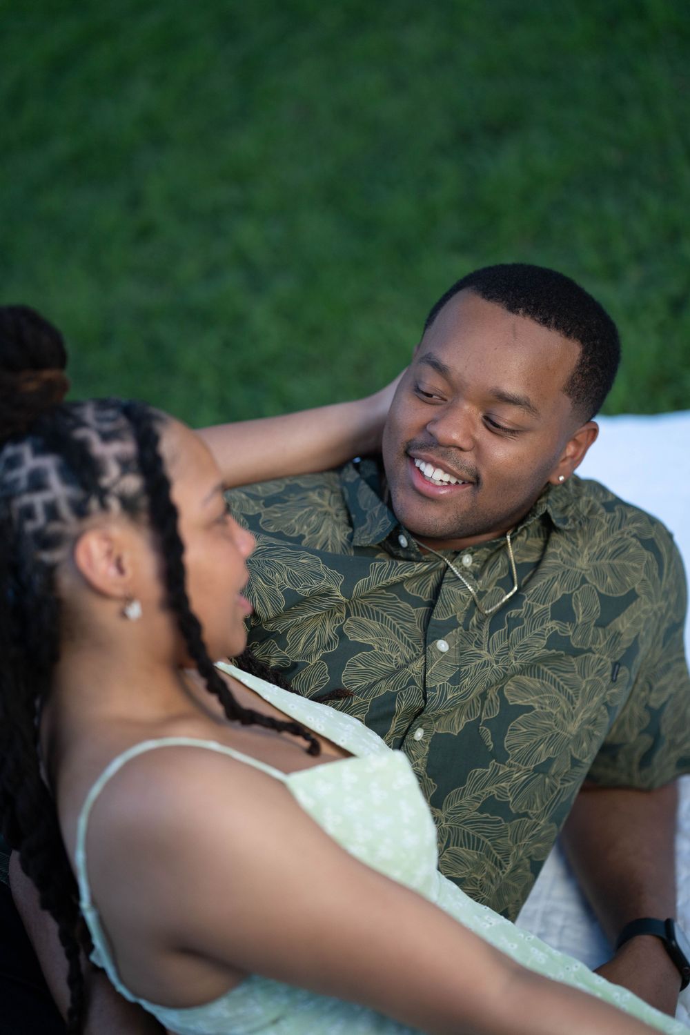 Happy couple sharing joyful moment outdoors on blanket.