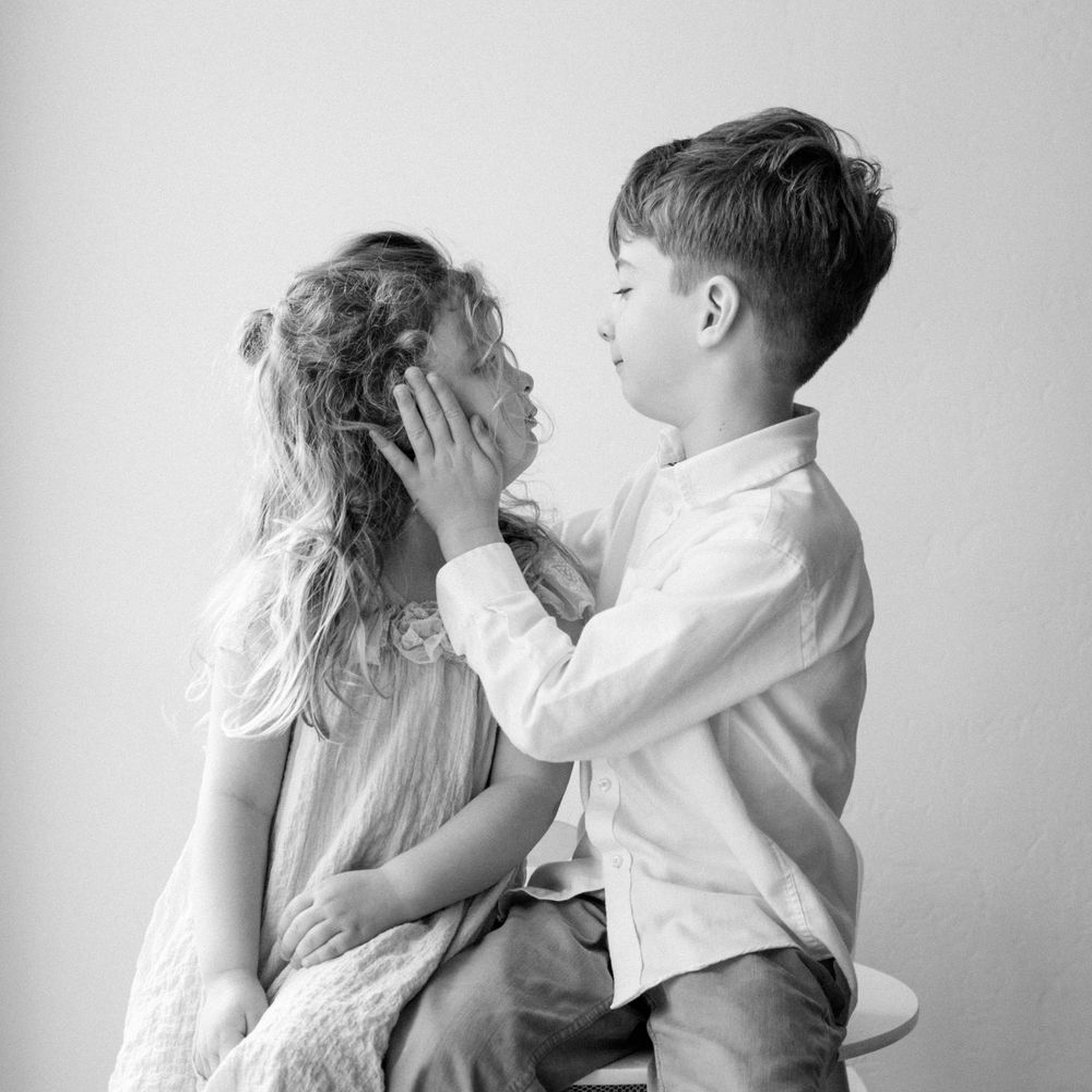 Black and white portrait of two children sharing a tender moment.