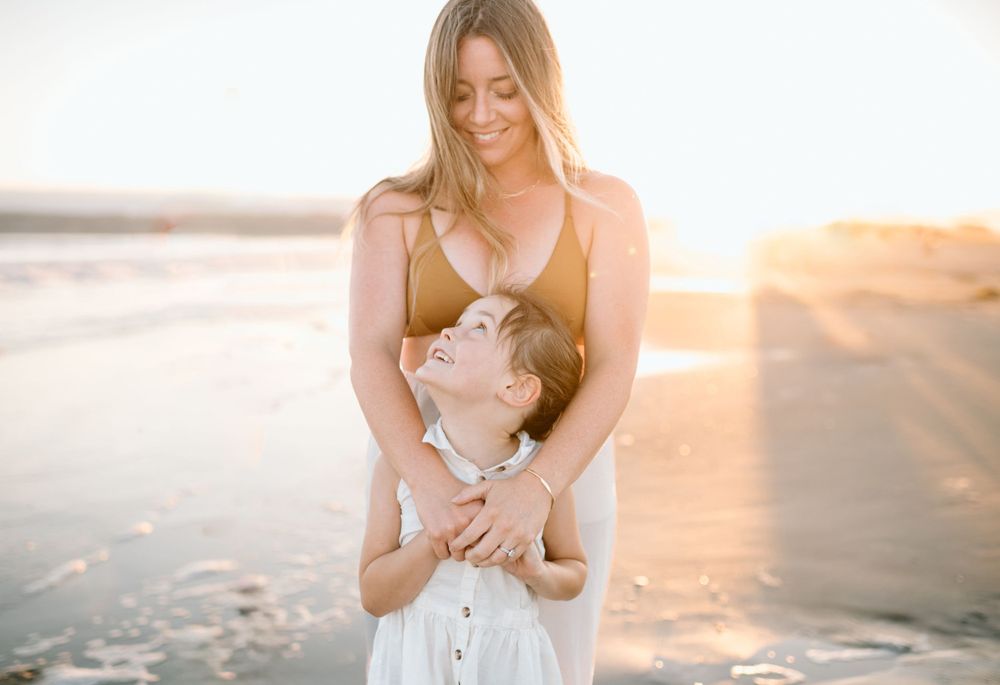 Mother and child sharing a tender moment at sunset on the beach during family photoshoot in San Diego.