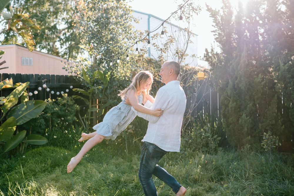 Romantic sunset dance in lush garden with string lights during family photoshoot in San Diego.