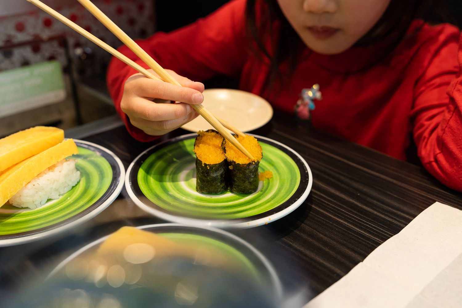 Child using chopsticks to eat a piece of sushi in Bellevue.