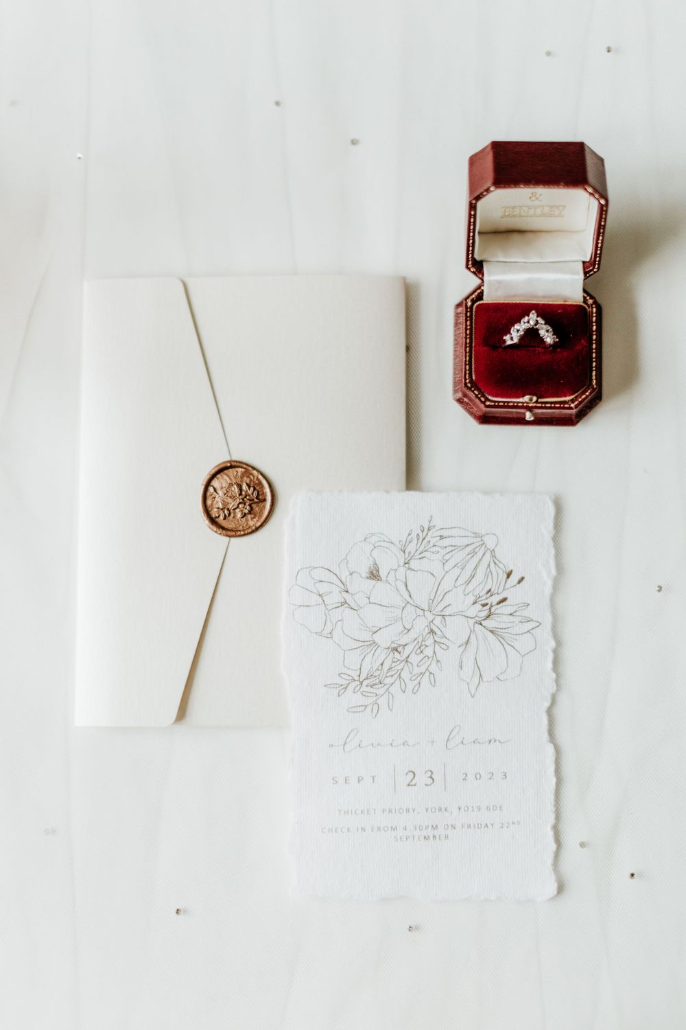 Wedding invitation suite with wax seal, floral design and burgundy ring box.