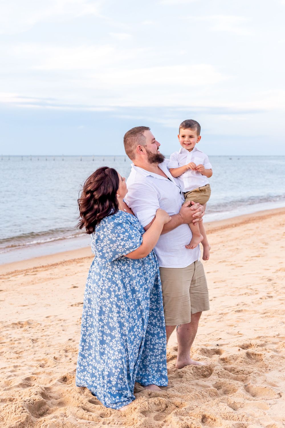 A family shares a moment together on a sandy beach at sunset.