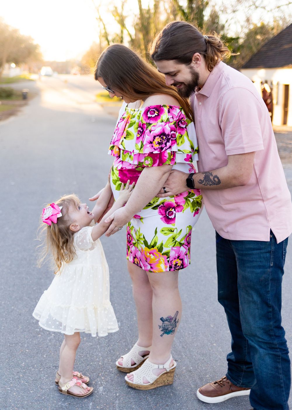 Sweet family moment on suburban street with floral dress and pink shirt.