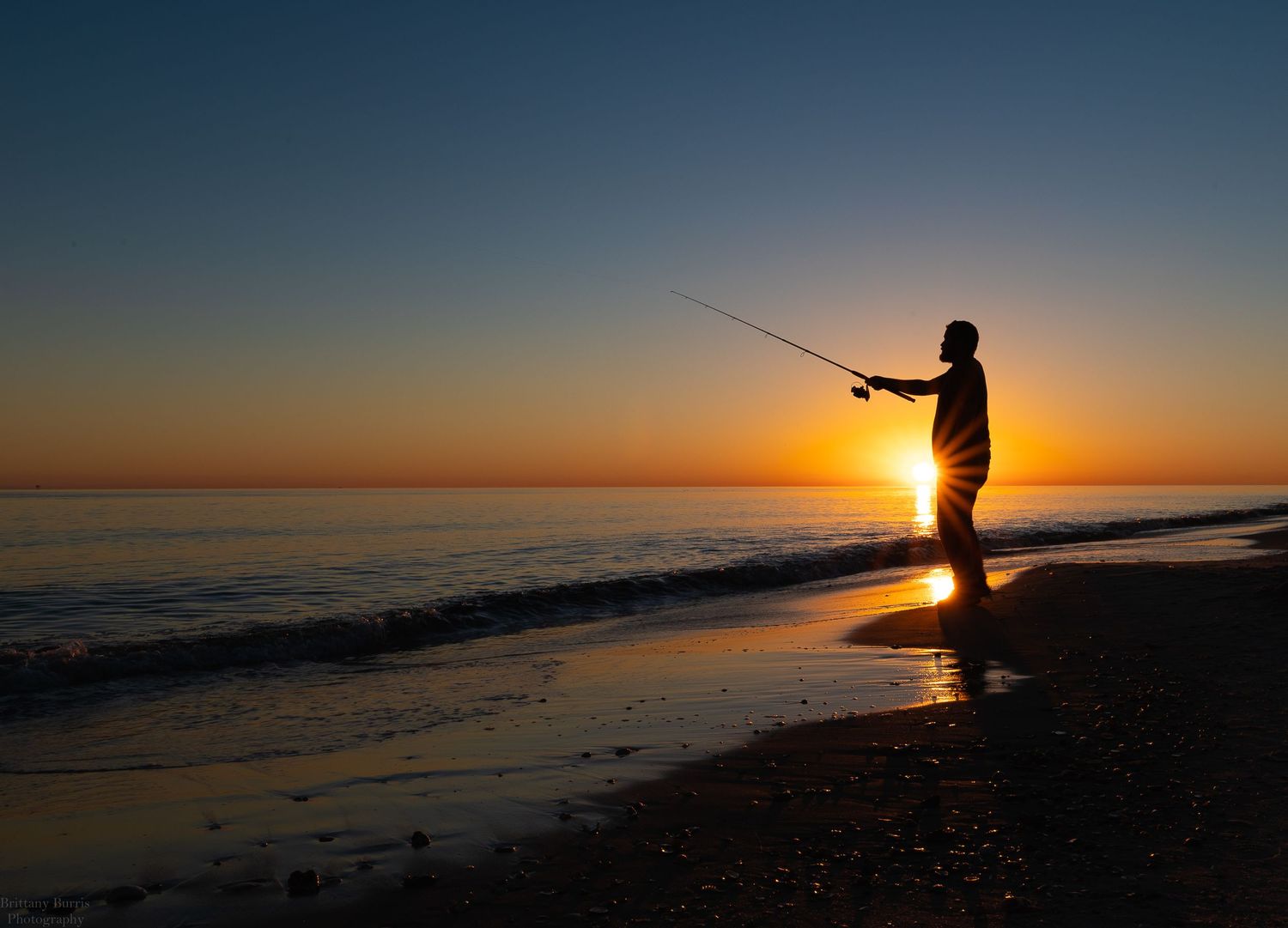 silhouette of man fishing on beach
