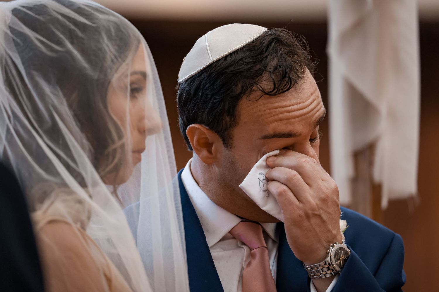 Emotional moment during Jewish wedding ceremony showing deep feelings through tearful gestures.