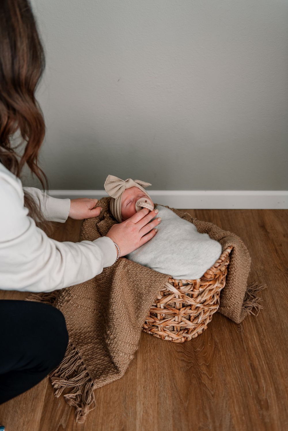 Close-up shots of hands arranging a brown textured blanket on wooden flooring.