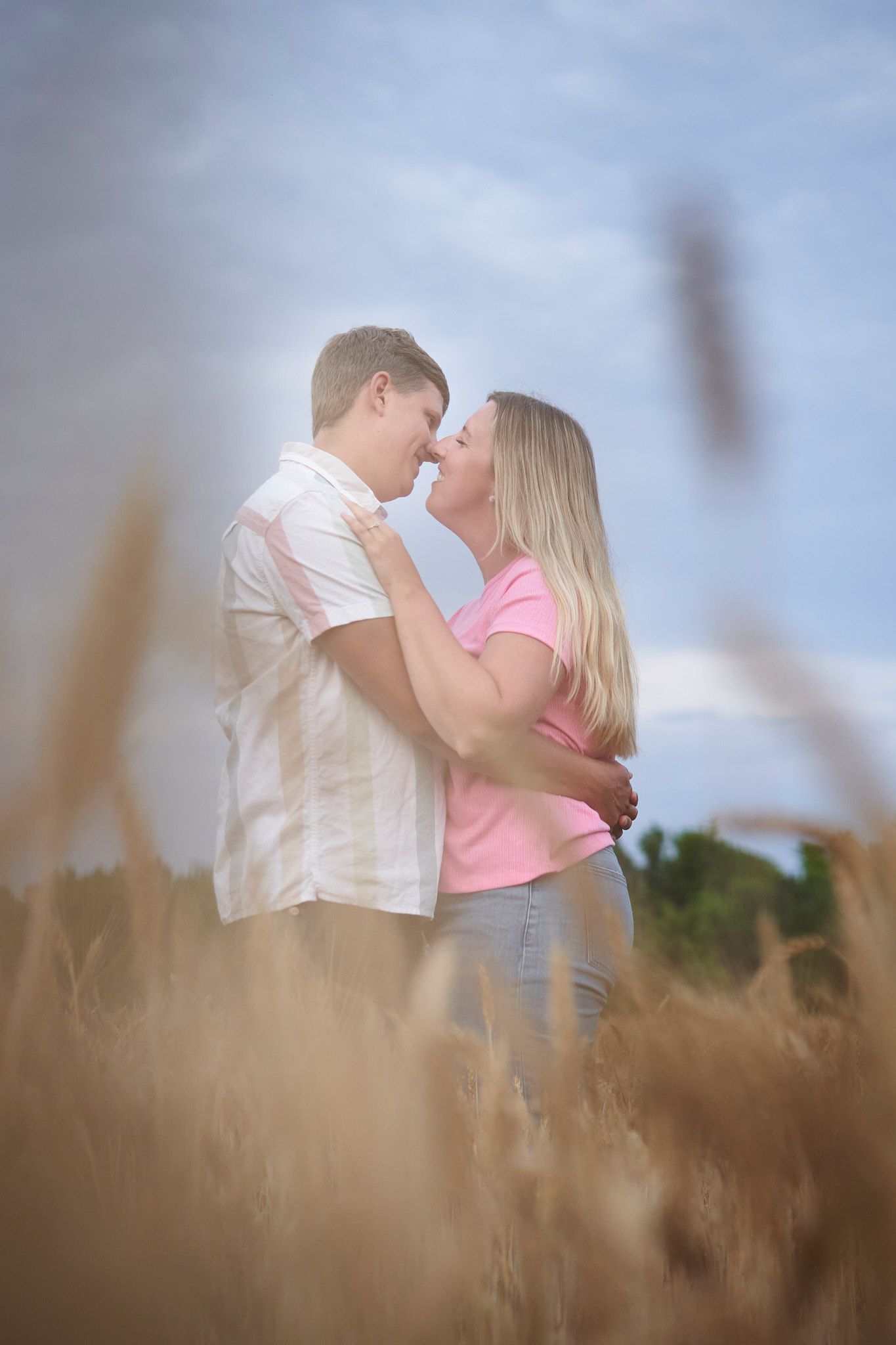 Romantic couple embracing in a wheat field on a cloudy day.