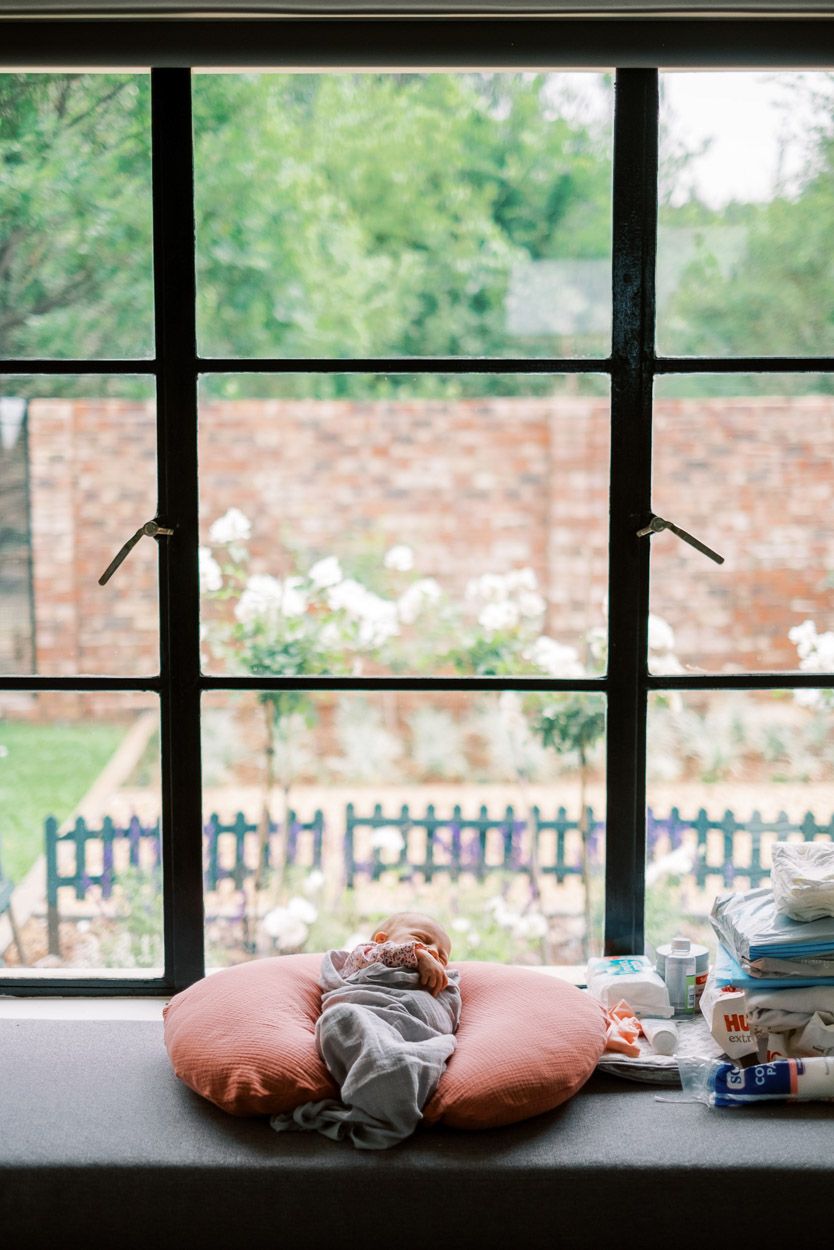 A baby lies in a window sill