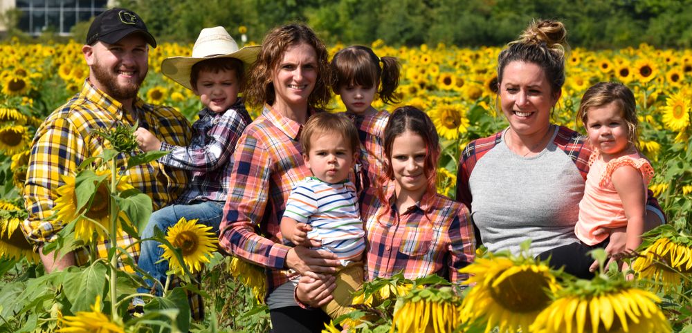 A group poses together in a vibrant sunflower field on a sunny day.