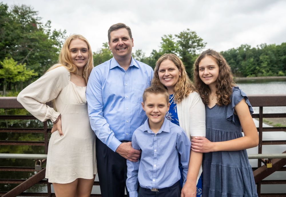 Casual family photo session outdoors with group posing together on wooden deck.