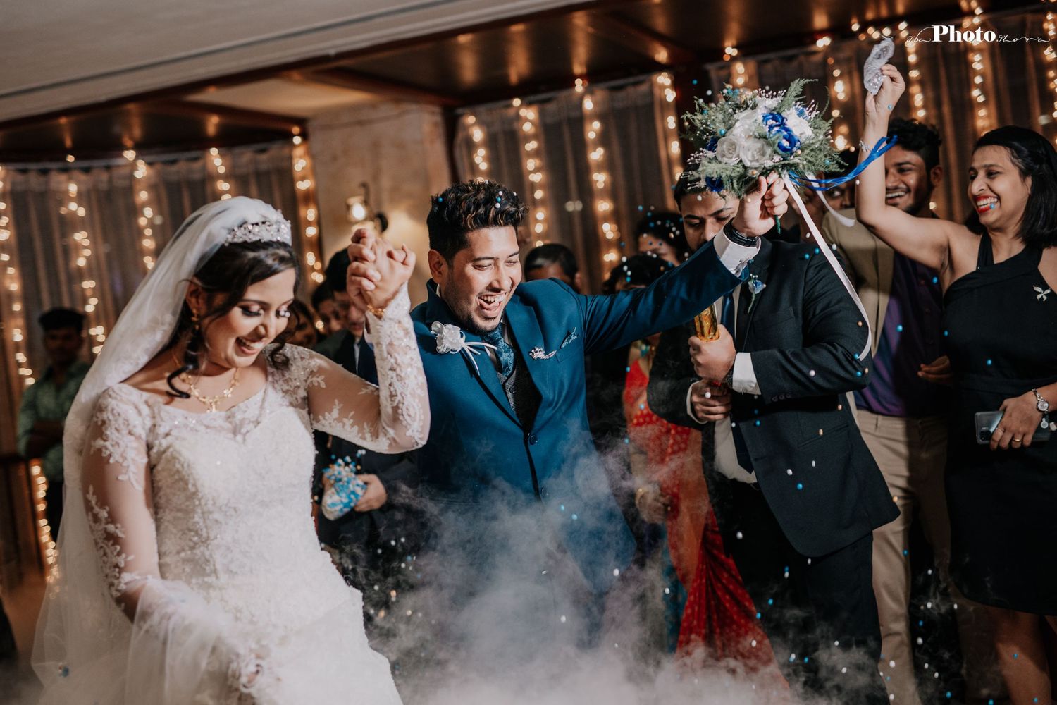 Wedding party celebrating with confetti and string lights in a festive indoor venue.
