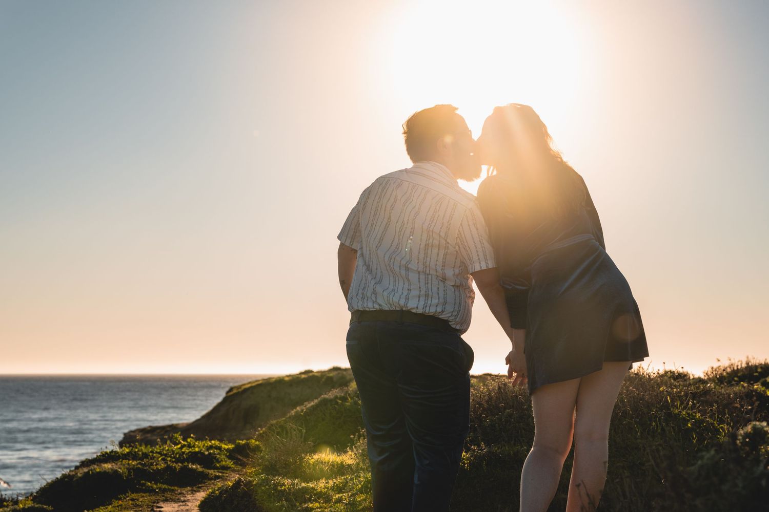 Engaged couple on a coastal cliff at sunset