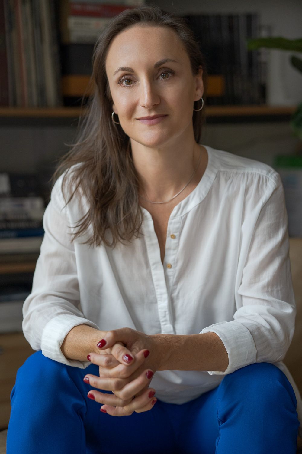 A woman in a white shirt and blue trousers is sitting.