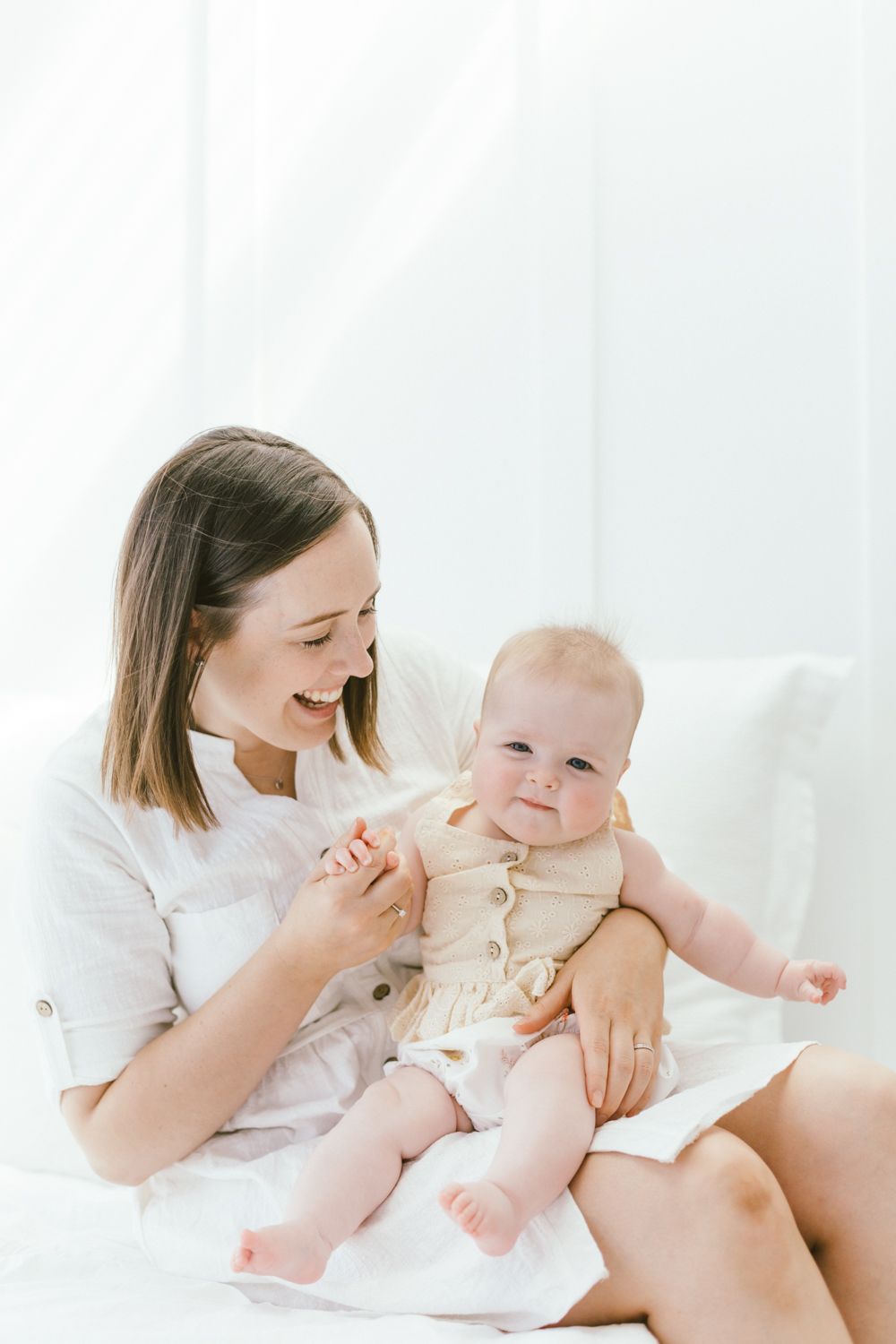 Sweet candid moment between parent and baby during white studio photoshoot.