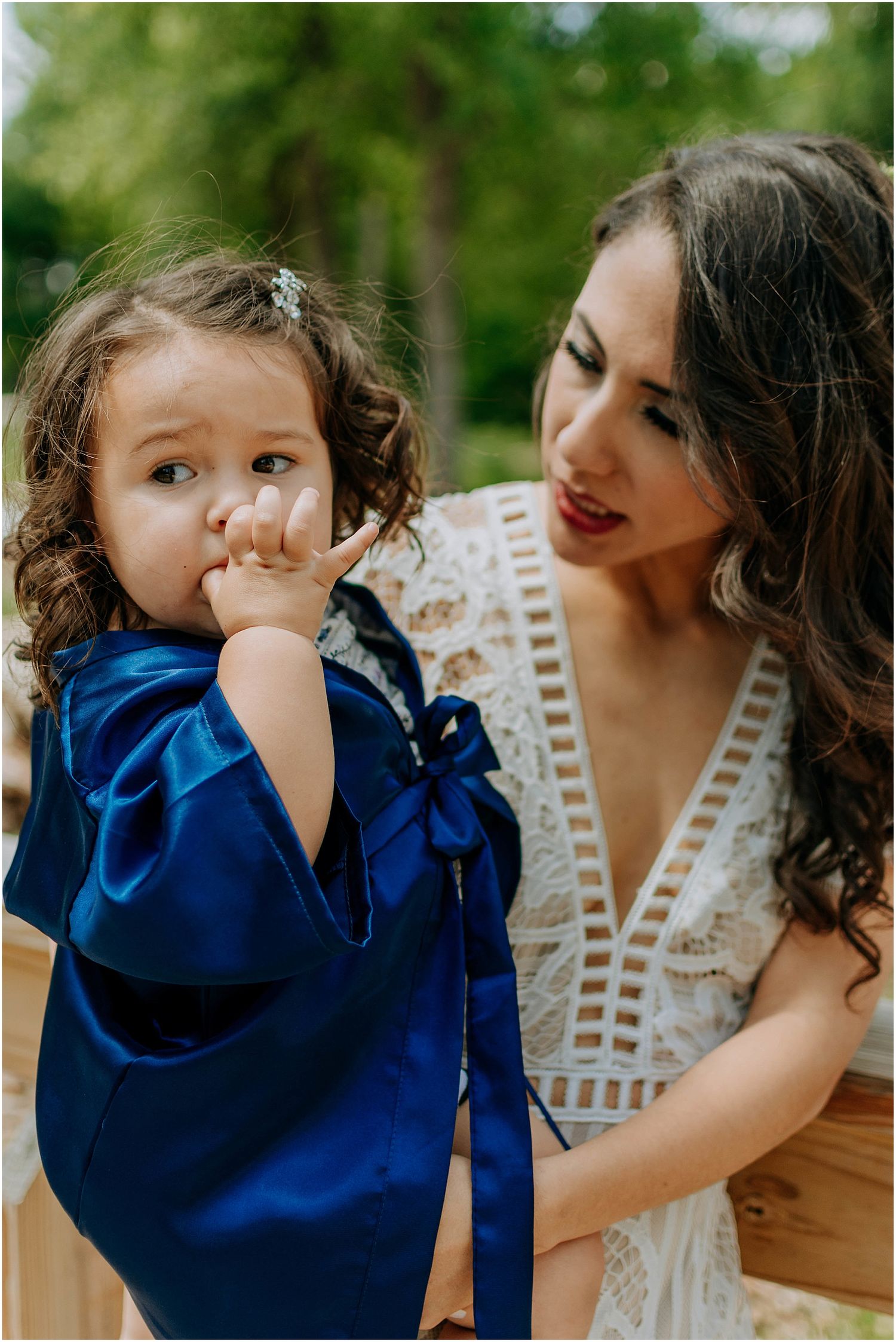 Sweet moment between woman in white lace dress and small child in navy blue outfit.