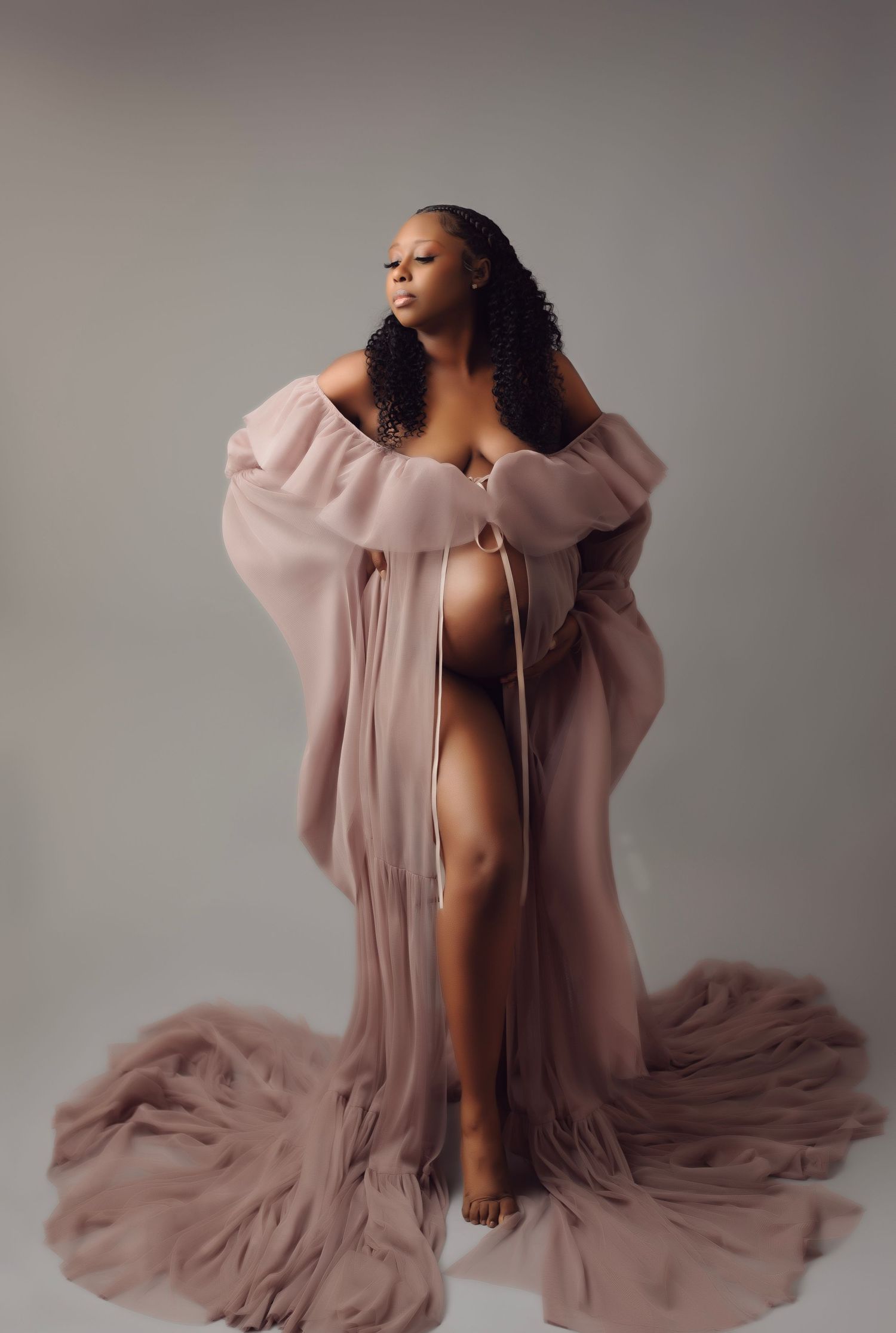 Artistic maternity portrait with flowing mauve fabric in studio setting.