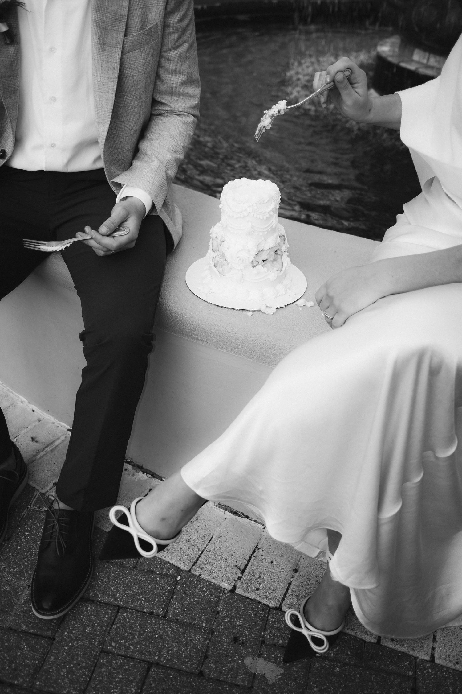 Black and white sequence of wedding cake being cut on outdoor patio.