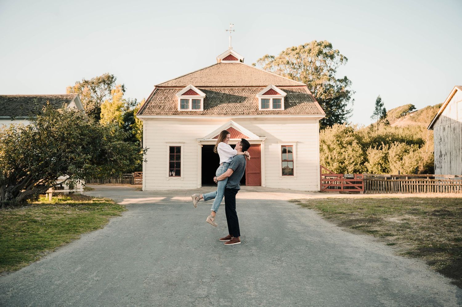 A romantic moment captured in front of a historic building with white walls and dormers.