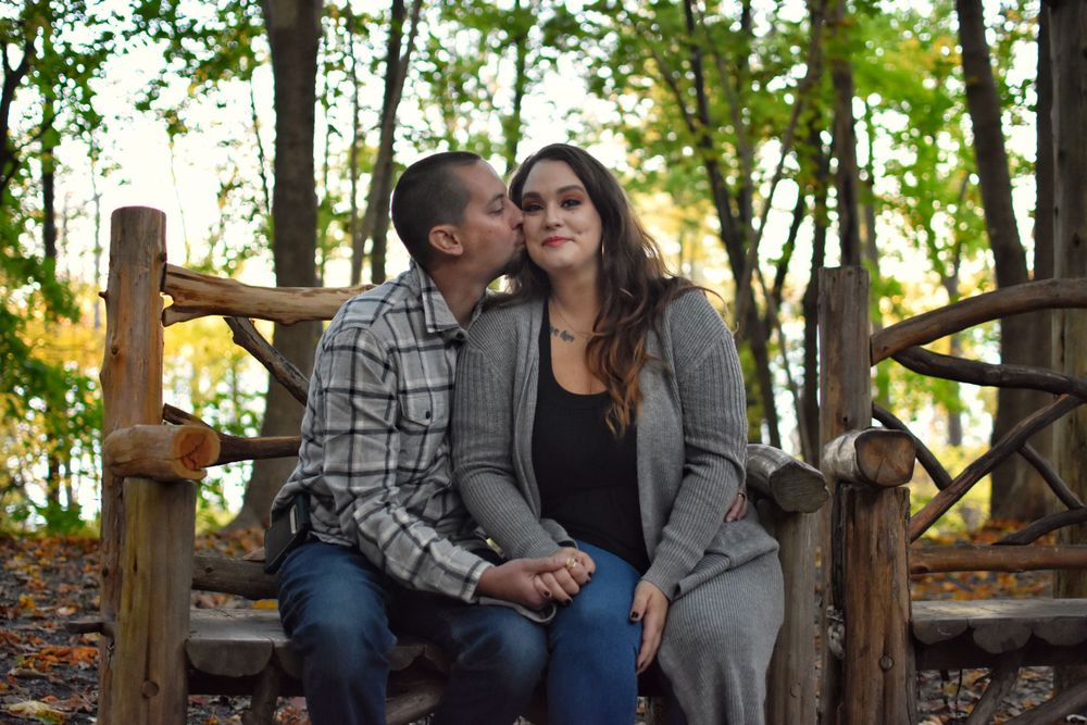 Husband and wife, rustic wood branch bench, kissing cheek, fall woodland foilage