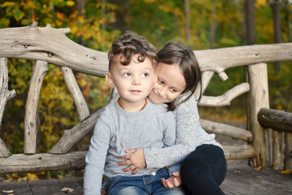 Brother and sister hugs at rustic branch bench