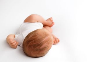 Looking down at the top of a baby's head while he is sleeping in a simple white jumper