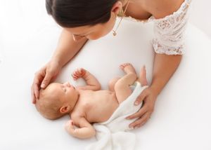 mother reaches down to touch her baby laying down on a beanbag