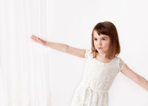 fancily dressed little girl holds her arms out like an airplane