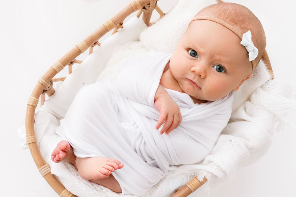 Newborn baby in a basket looking up at camera with an expression attitude