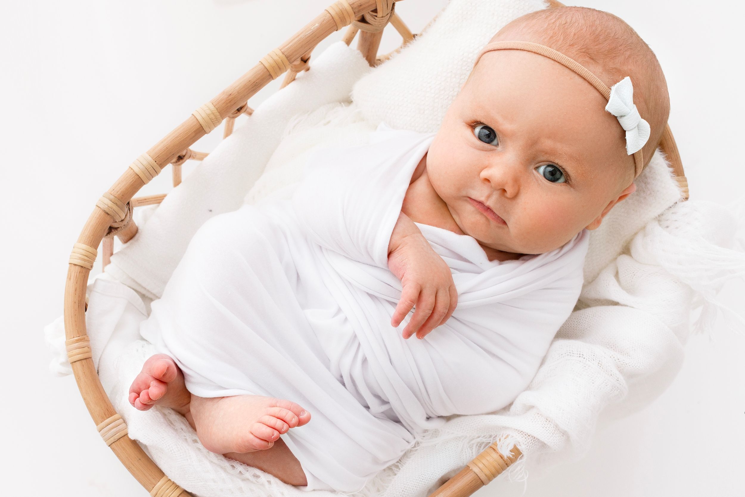 Newborn baby in a basket looking up at camera with an expression attitude