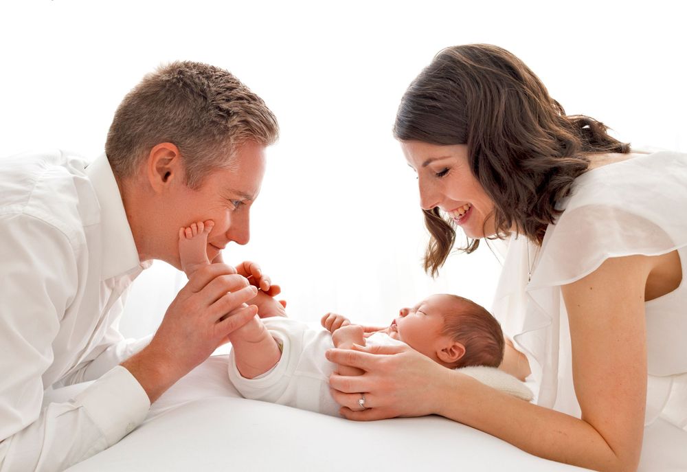 parents smile at new baby as they play with his fingers and toes