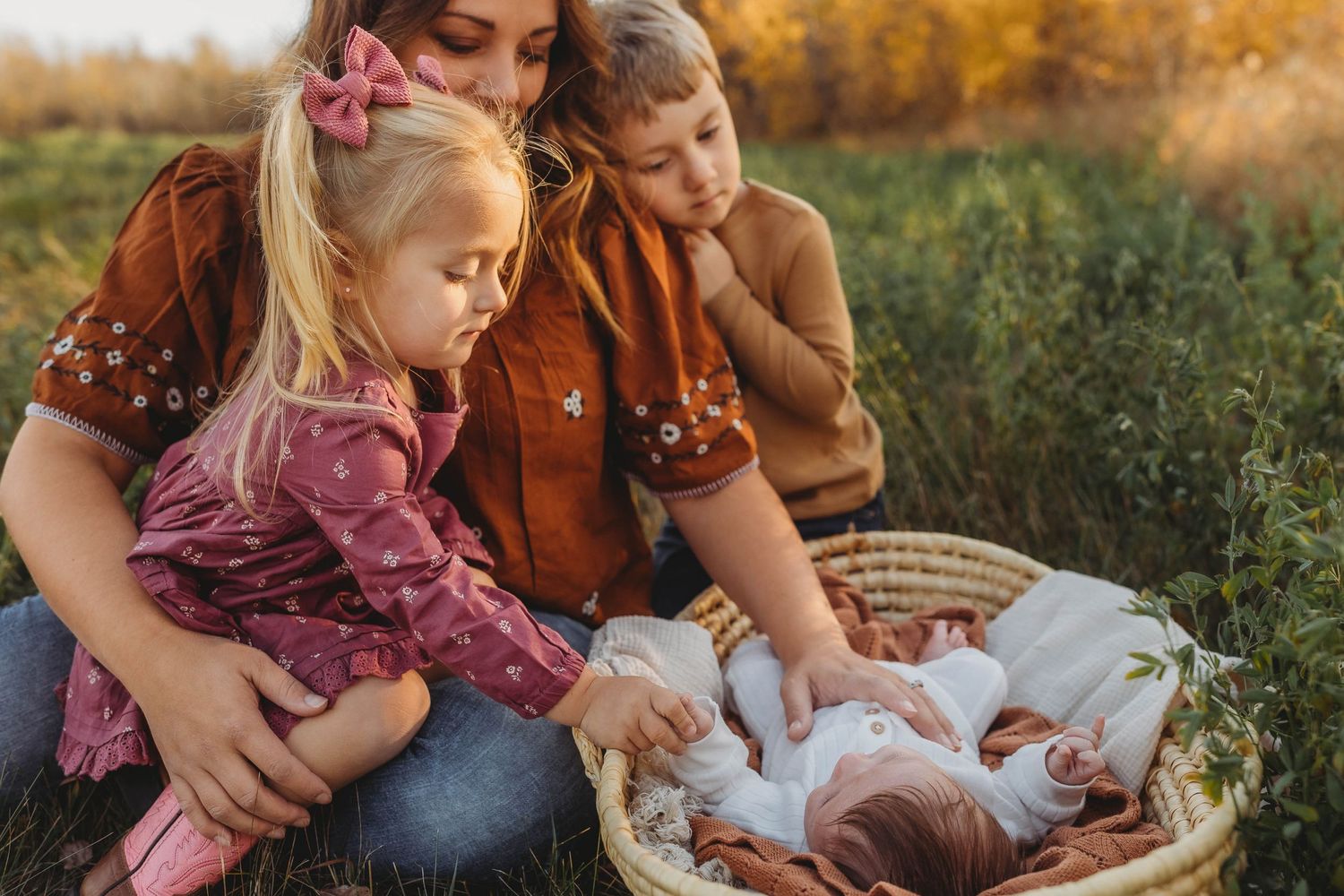 A tender family gathering on a blanket during golden hour in a field.