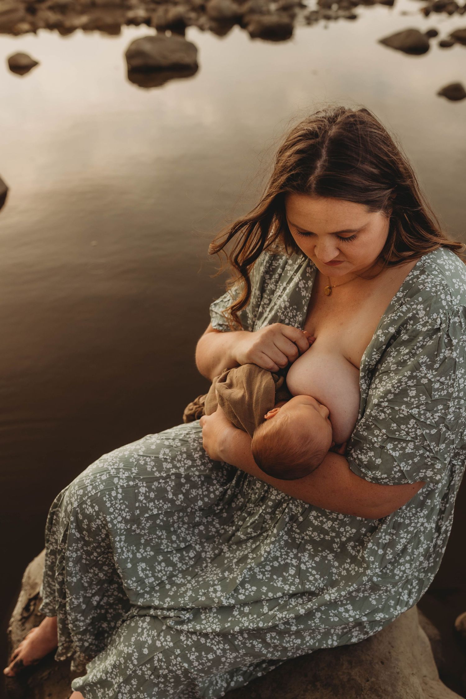 An intimate nurturing moment captured by a rocky shoreline at sunset.