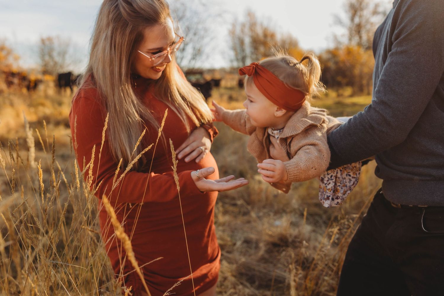 A family moment captured in warm autumn sunlight amidst tall grass.