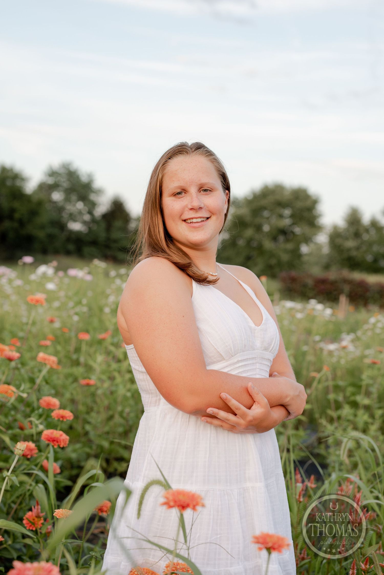 A summer portrait featuring a white dress and coral-colored flowers in a garden setting.