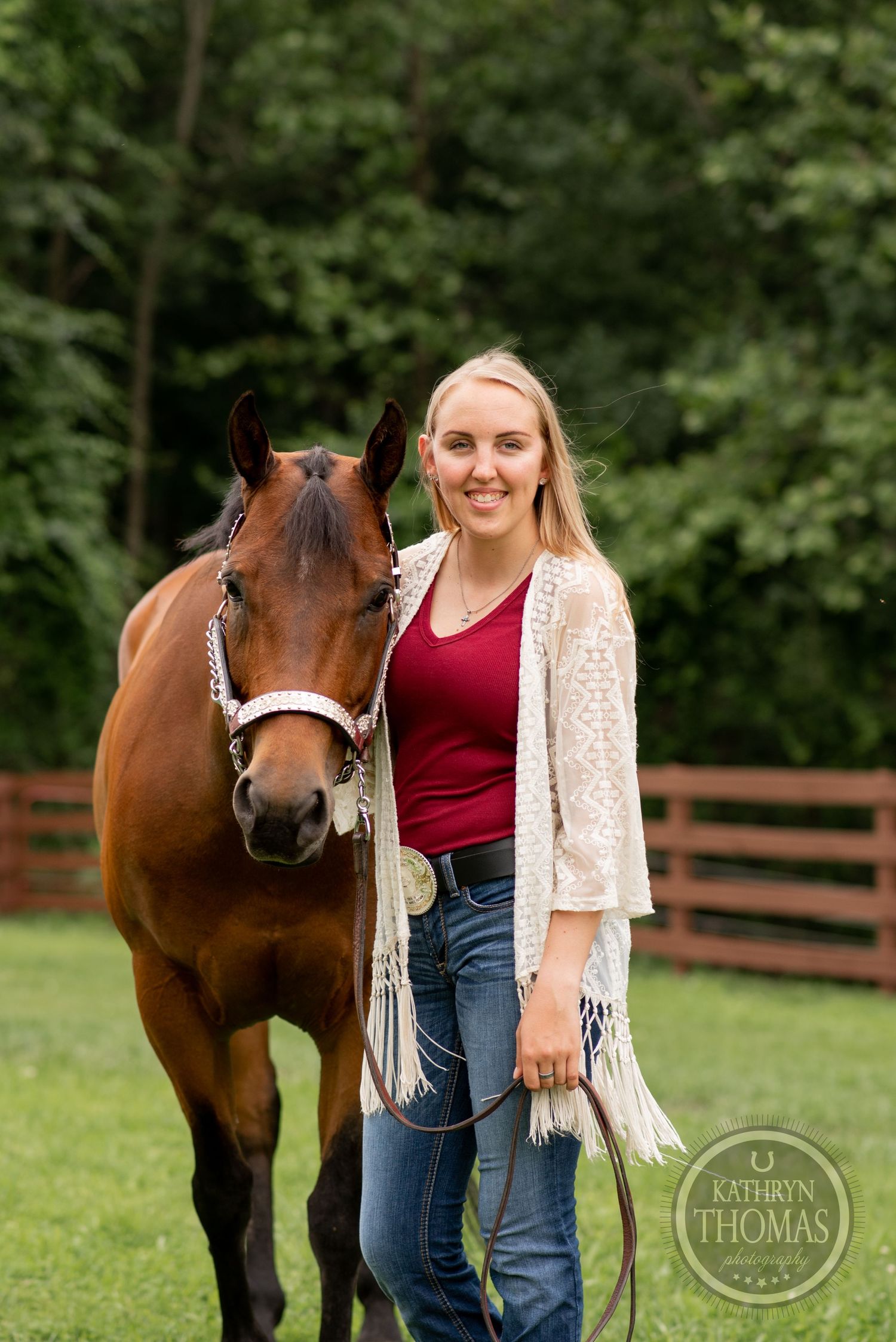 A beautiful brown horse stands next to someone in a white cardigan and red top.