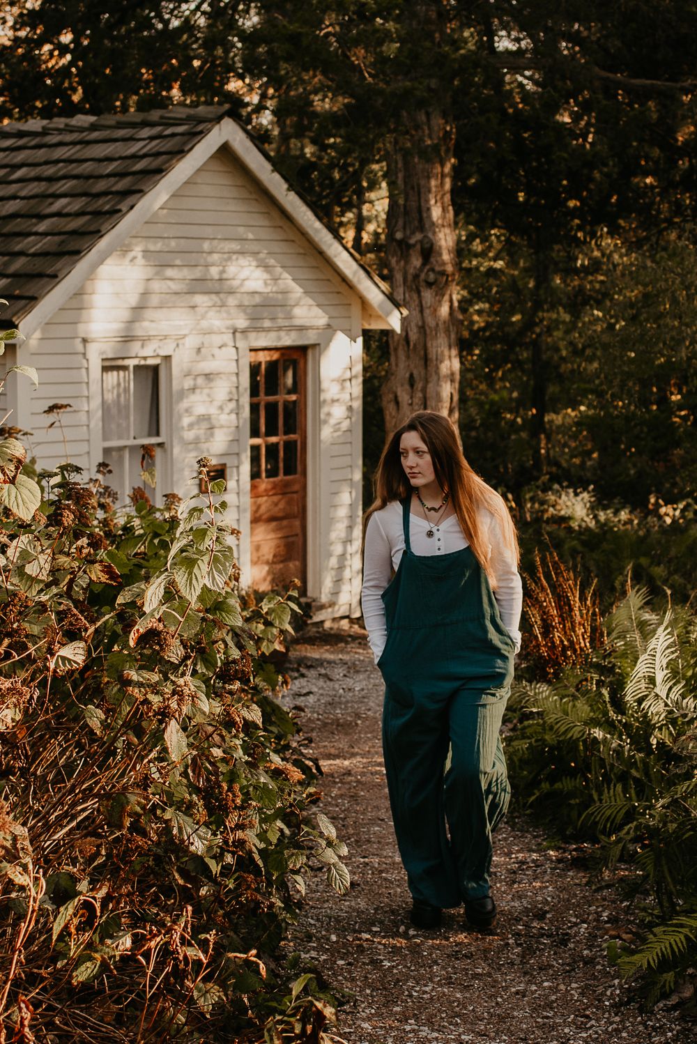 Outdoor photography session near charming white garden sheds surrounded by fall foliage.