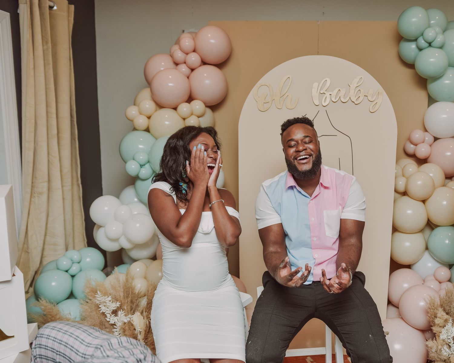 Gender reveal celebration setup with pastel balloon arch and decorative background.