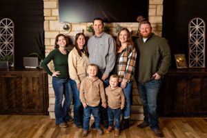 group wearing coordinated winter outfits poses together for family portrait in front of a rustic wooden backdrop.Janesville, WI
Brodhead WI